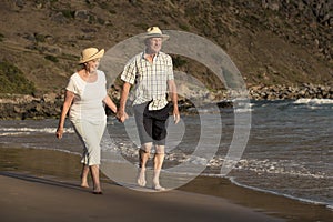 Lovely senior mature couple on their 60s or 70s retired walking happy and relaxed on beach sea shore in romantic aging together