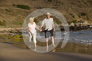 Lovely senior mature couple on their 60s or 70s retired walking happy and relaxed on beach sea shore in romantic aging together