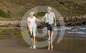 Lovely senior mature couple on their 60s or 70s retired walking happy and relaxed on beach sea shore in romantic aging together