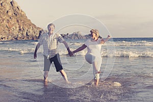 Lovely senior mature couple on their 60s or 70s retired walking happy and relaxed on beach sea shore in romantic aging together