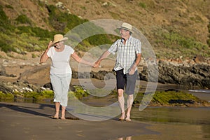 Lovely senior mature couple on their 60s or 70s retired walking happy and relaxed on beach sea shore in romantic aging together