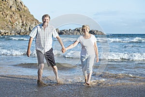 Lovely senior mature couple on their 60s or 70s retired walking happy and relaxed on beach sea shore in romantic aging together