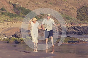 Lovely senior mature couple on their 60s or 70s retired walking happy and relaxed on beach sea shore in romantic aging together