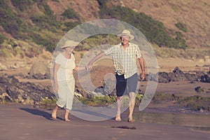 Lovely senior mature couple on their 60s or 70s retired walking happy and relaxed on beach sea shore in romantic aging together