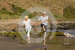 Lovely senior mature couple on their 60s or 70s retired walking happy and relaxed on beach sea shore in romantic aging together