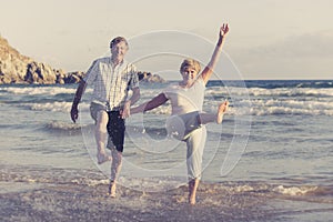 Lovely senior mature couple on their 60s or 70s retired walking happy and relaxed on beach sea shore in romantic aging together