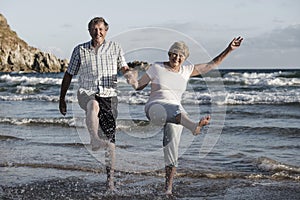 Lovely senior mature couple on their 60s or 70s retired walking happy and relaxed on beach sea shore in romantic aging together