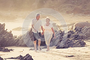 Lovely senior mature couple on their 60s or 70s retired walking happy and relaxed on beach sea shore in romantic aging together