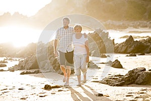 Lovely senior mature couple on their 60s or 70s retired walking happy and relaxed on beach sea shore in romantic aging together