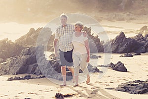 Lovely senior mature couple on their 60s or 70s retired walking happy and relaxed on beach sea shore in romantic aging together