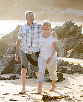 Lovely senior mature couple on their 60s or 70s retired walking happy and relaxed on beach sea shore in romantic aging together