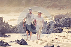 Lovely senior mature couple on their 60s or 70s retired walking happy and relaxed on beach sea shore in romantic aging together