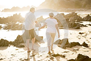 Lovely senior mature couple on their 60s or 70s retired walking happy and relaxed on beach sea shore in romantic aging together