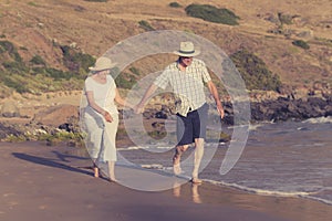 Lovely senior mature couple on their 60s or 70s retired walking happy and relaxed on beach sea shore in romantic aging together