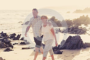 Lovely senior mature couple on their 60s or 70s retired walking happy and relaxed on beach sea shore in romantic aging together