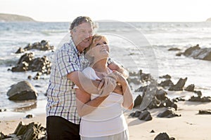 Lovely senior mature couple on their 60s or 70s retired walking happy and relaxed on beach sea shore in romantic aging together