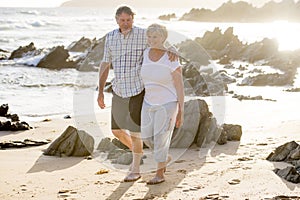 Lovely senior mature couple on their 60s or 70s retired walking happy and relaxed on beach sea shore in romantic aging together