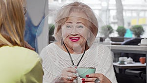Lovely senior woman laughing talking to her daughter over cup of tea