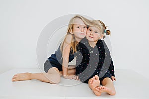 Lovely siblings sitting on a table with their feet up. Over white wall