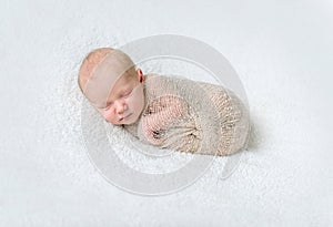 Lovely sleeping baby wrapped in beige diaper