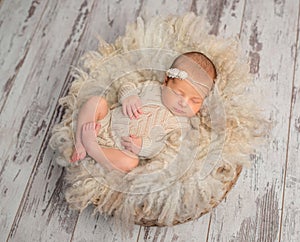 Lovely sleeping newborn baby in knitted jumpsuit in basket