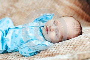 Lovely sleeping newborn boy is dressed in blue overalls