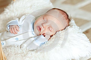 Lovely sleeping newborn boy is dressed in overalls and booties lies in the basket