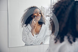 Lovely smiling lady massaging her facial skin