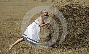 Lovely smiling woman plying with haystack outdoors photo