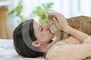 Young Asian Woman Kissing Cat in Bedroom Morning