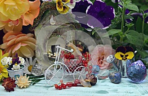 Lovely summer still life with funny snail, tiny bicycle, doll house, flowers and berries in the garden
