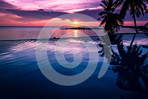 Lovely sunset by infinity pool over the calm sea