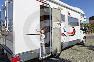 Lovely sweet five year old caucasian boy in the morning peeking out of his motorhome in pajamas