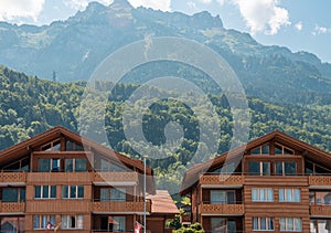 Lovely Swiss wooden chalet with mountains and forest in background.