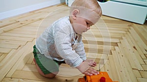 Lovely toddler boy playing with toy car on floor