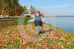 Lovely toddler boy running in autumn outdoors