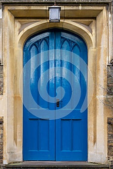 Blue large wooden church door with stone archway & lantern on top