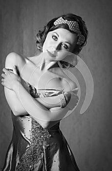 Lovely twenties woman wearing diamond hair accessory and bracelet, posing in a vintage grey evening dress