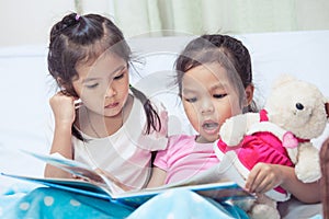 Lovely twin sister two child girls having fun to read a cartoon