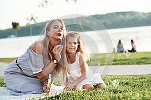 Lovely weather for an entertainment. Photo of young mother and her daughter having good time on the green grass with