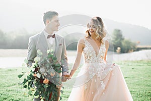 Lovely wedding couple, bride and groom posing in field during sunset