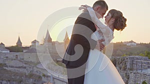Lovely wedding couple kisses each other and embraces near the castle sunset 4k