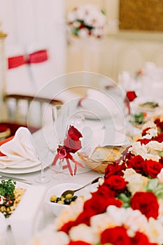 Lovely wedding table set. The champagne glass is decorated with red roses and ribbons.