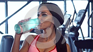 Lovely woman is drinking water in the gym