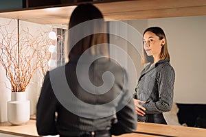 Lovely woman looking at her reflection in the mirror