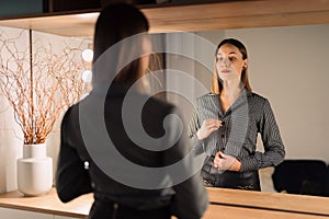 Lovely woman looking at her reflection in the mirror