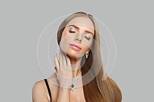 Lovely woman with makeup wearing jewelry necklace with sapphire and diamond on grey background