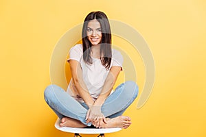 Lovely woman sititng on the chair over yellow