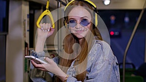 Lovely woman wearing headphones listening music, funny relax dancing while traveling by bus to city