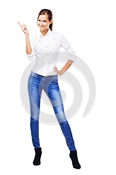 Lovely woman in white shirt and blue jeans pointing at copyspace